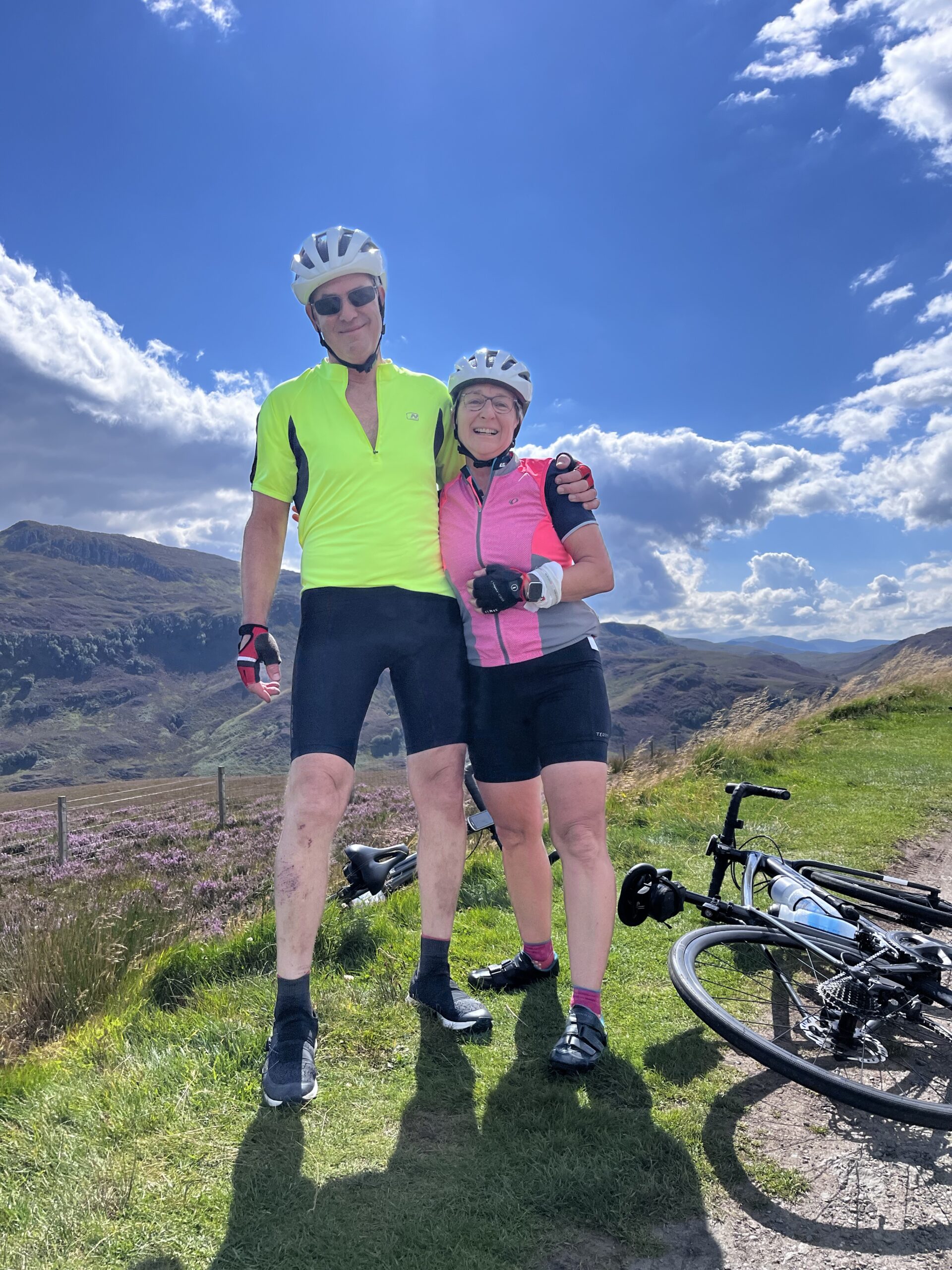 Cycling couple with scenic rolling hills behind them