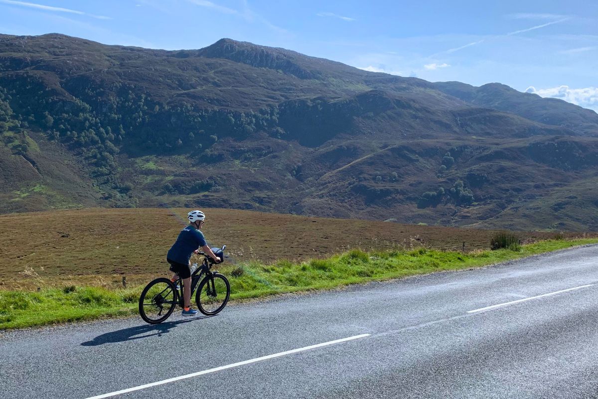 Cyclist riding with rolling hills in background