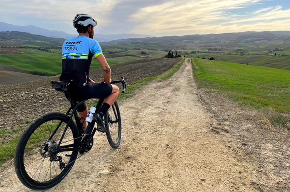 Rider standing with a back toward camera looking at horizont of Tuscan countryside