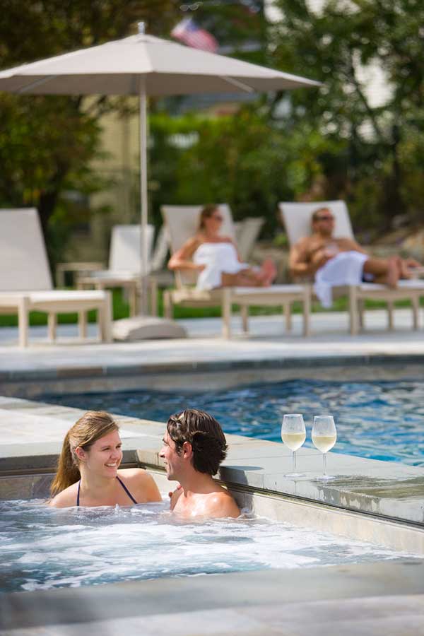 Couple enjoying the hotel pool and other relaxing in lounge chairs nearby