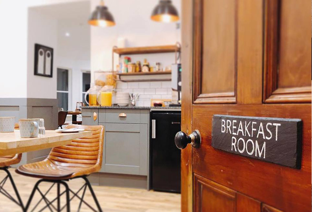 Wooden door labelled breakfast room opens to a kitchen and dining area