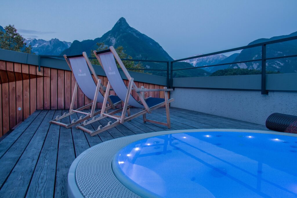 Outdoor hot tub with deck chairs looking at a mountain view