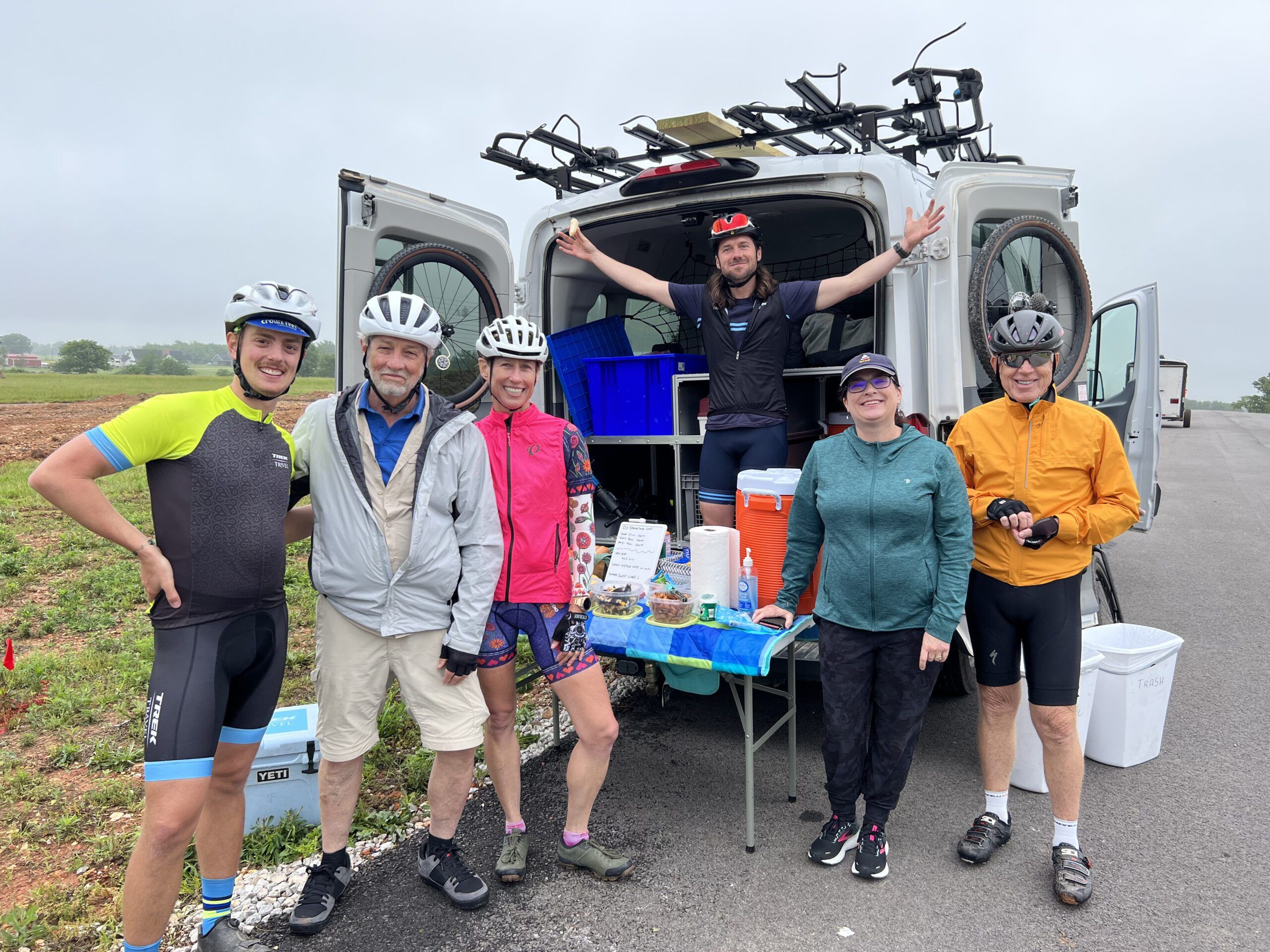 Group of cyclists in front of Trek Travel van and snack table