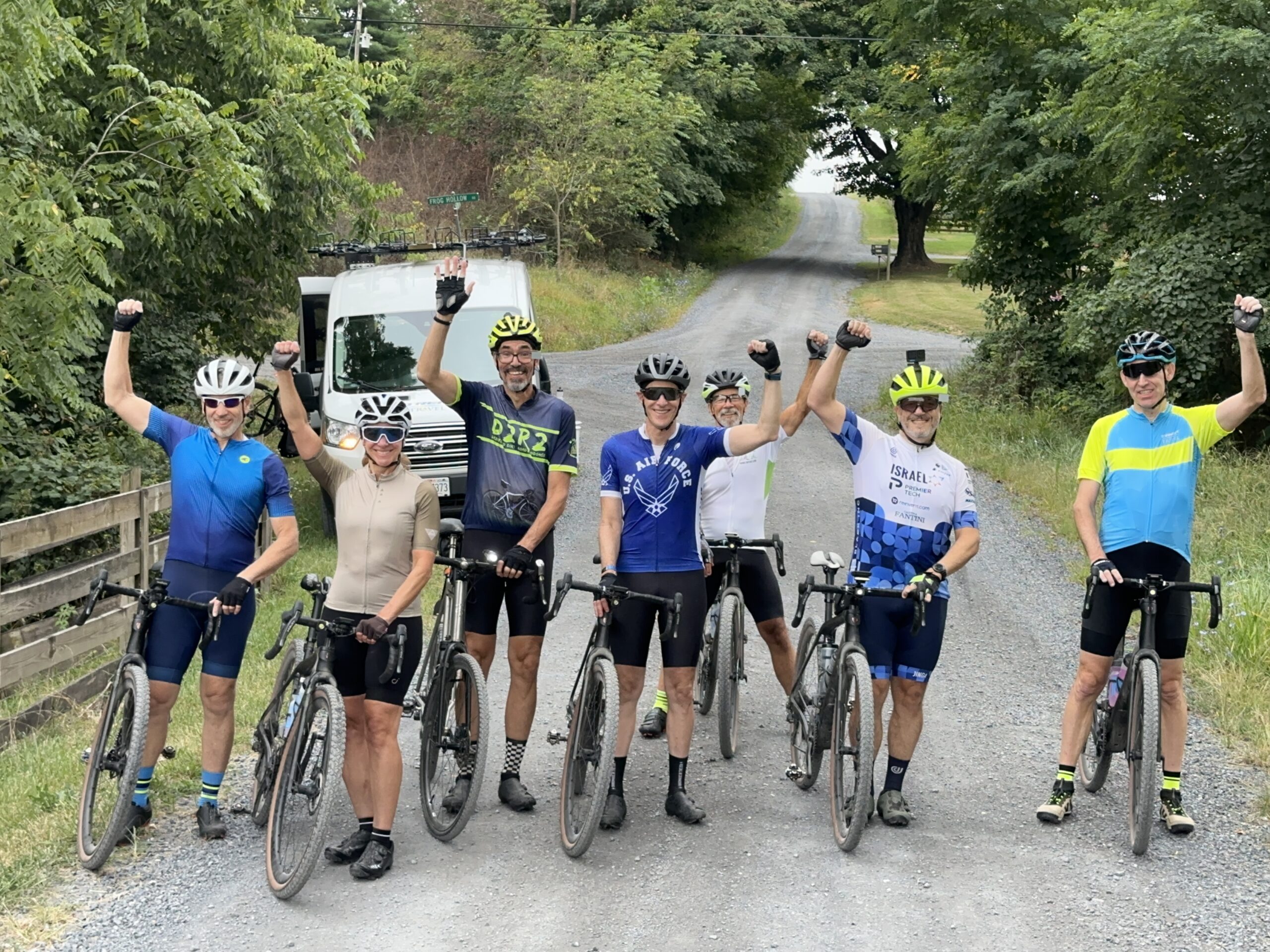 Group of cyclists on dirt road with hands in the air triumphantly