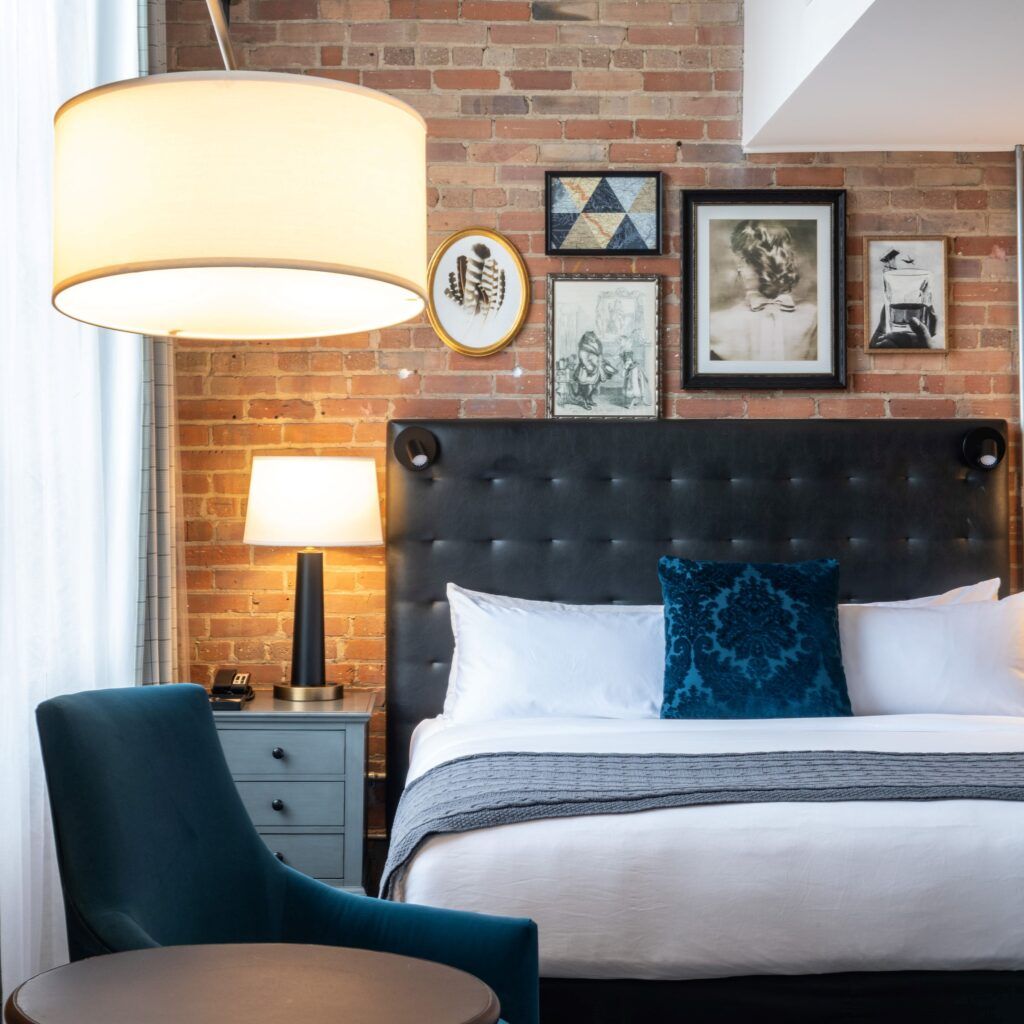 Interior view of hotel room with King bed brick wall and lamp