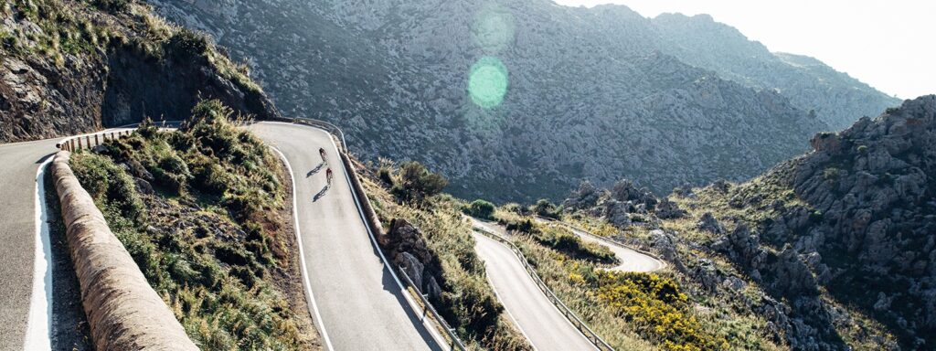 two cyclists riding their bikes up a hill in mallorca, spain