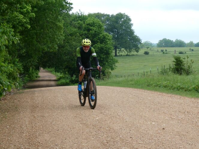 Cyclist on dirt road with green foliage in background