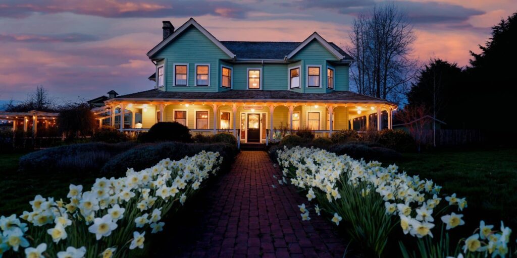 Evening view of Hotel Edenwild Inn with lit porch and daffodils