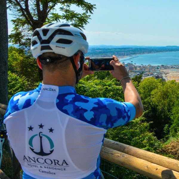 Man in cycling clothes taking photo of sea view