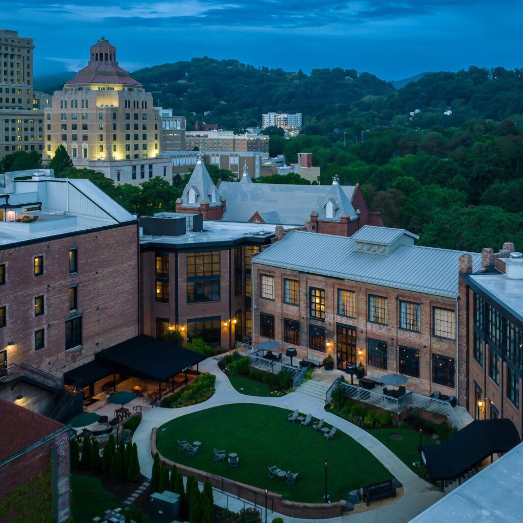 Aerial view of the courtyard of the Foundry Hotel at dusk with Asheville City Hall in the background