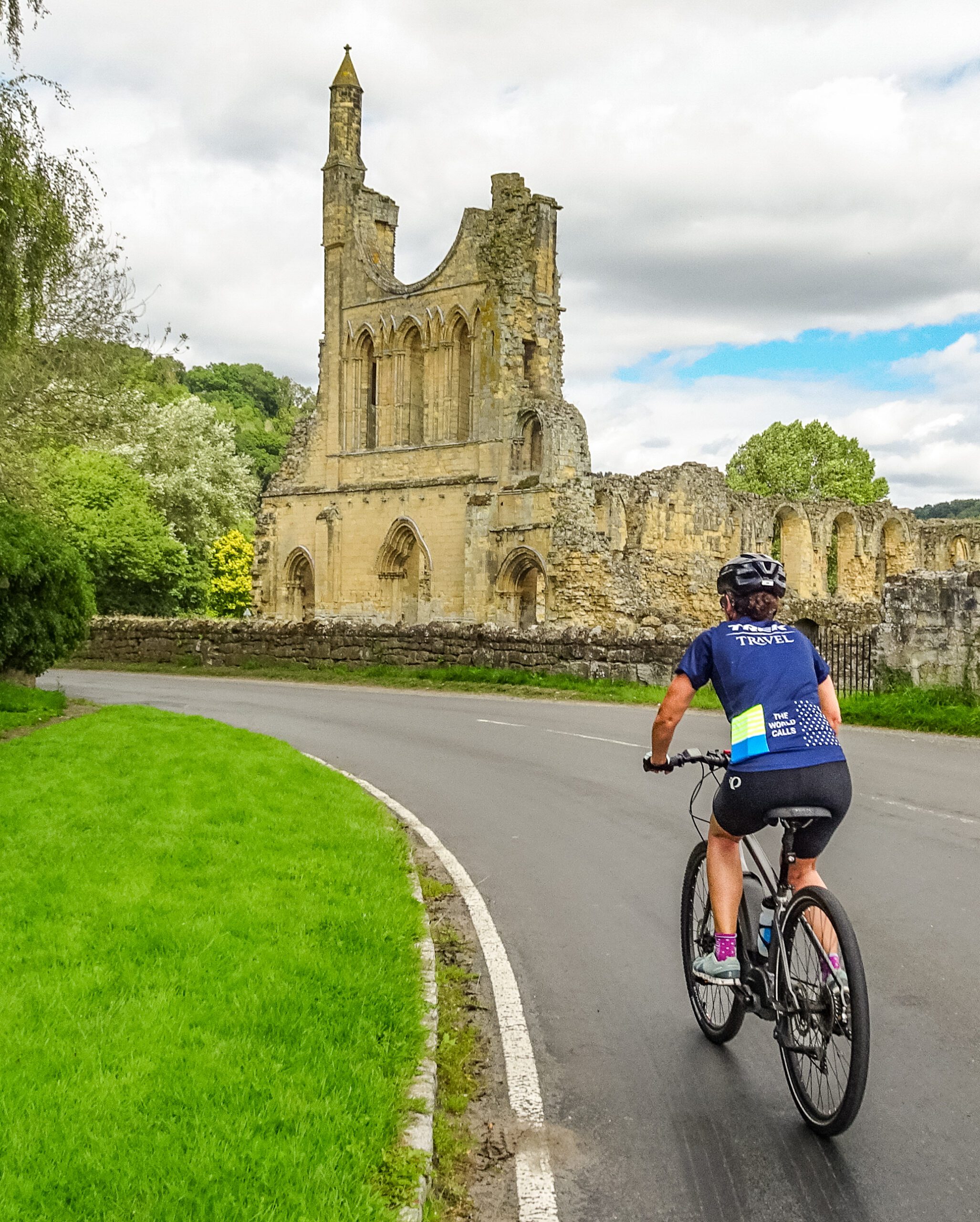 A cyclist rides toward an old stone church in ruins