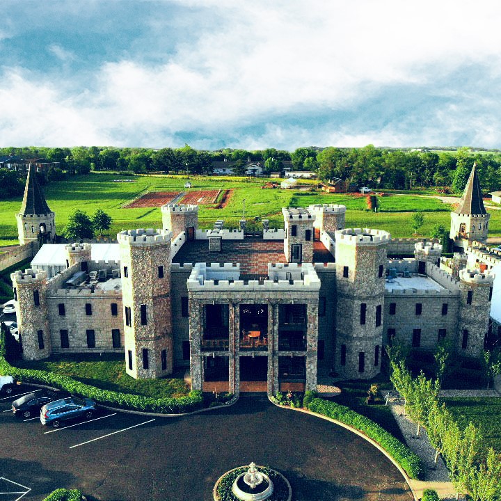 Aerial view of the Kentucky Castle from the front with clouds and landscape in the background