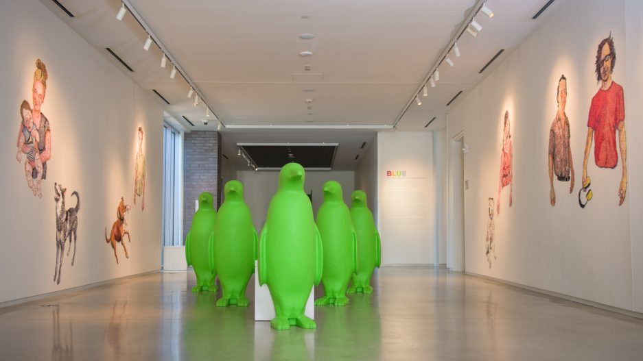Green penquin sculptures set up like bowling pins in hallway