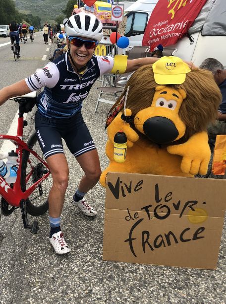 A cyclist smiling next to a sign at the Tour de France