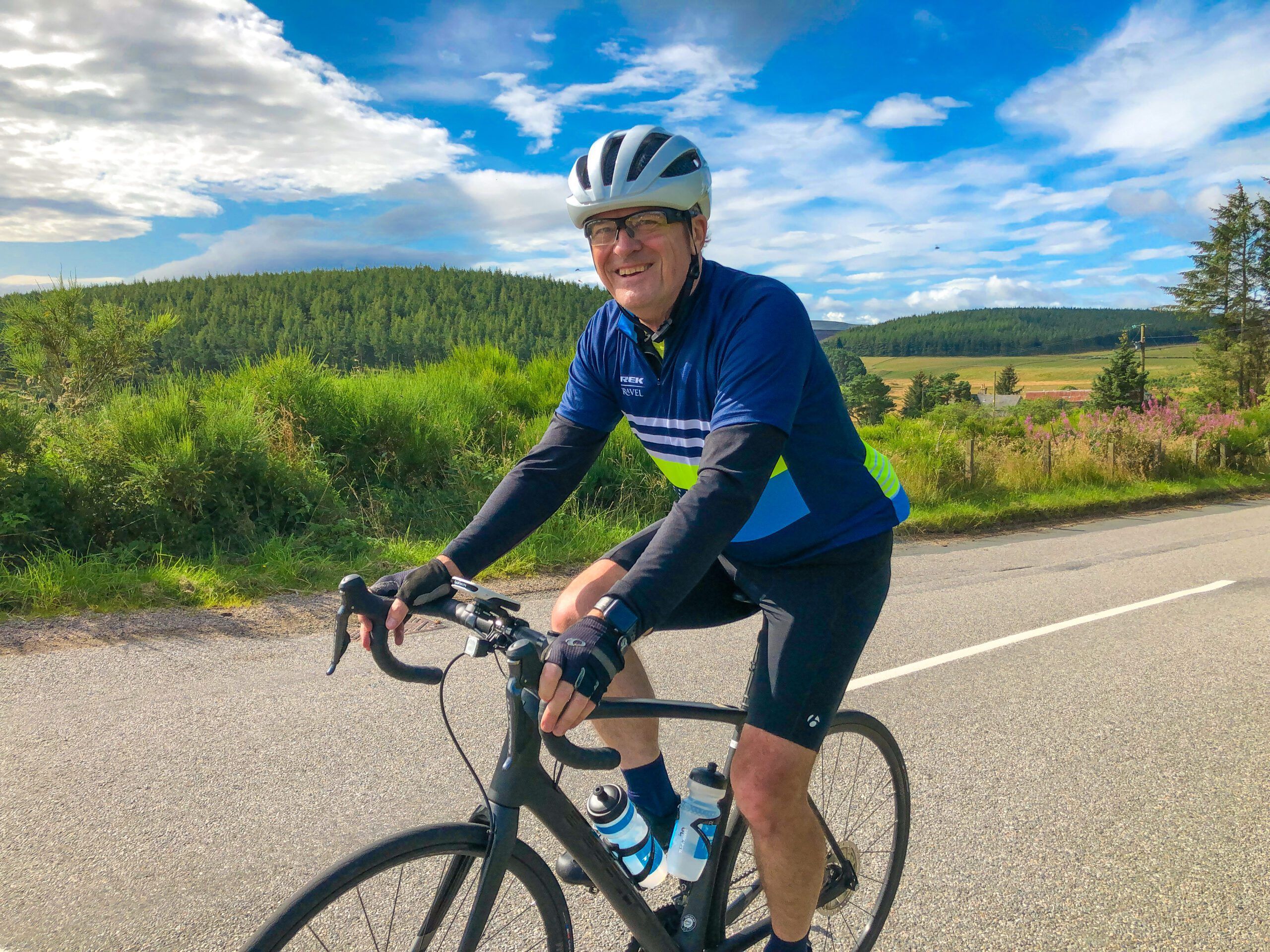 person riding their bike smiling on a beautiful sunny day with blue sky