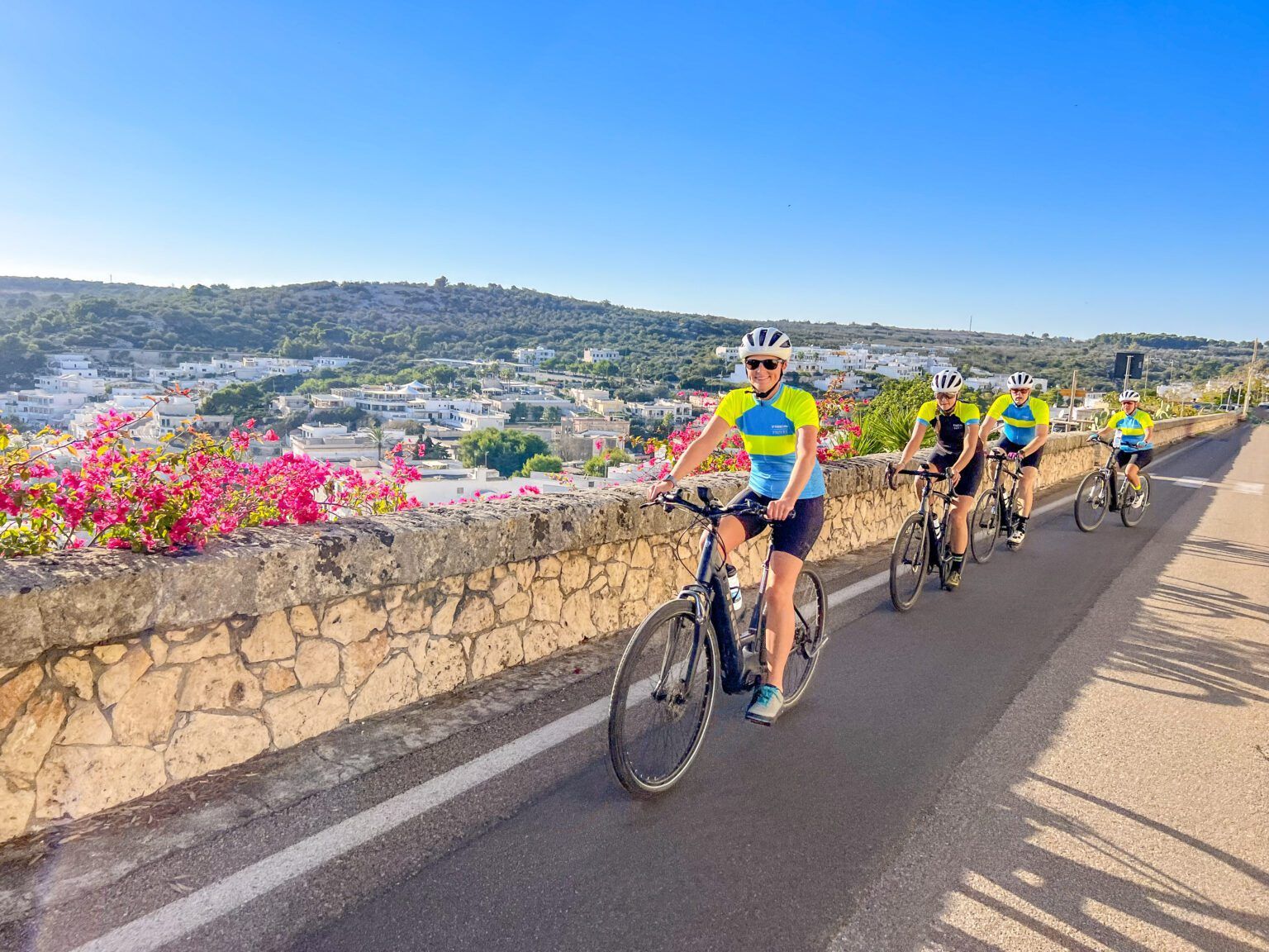 people riding their bikes along a paved road in Puglia