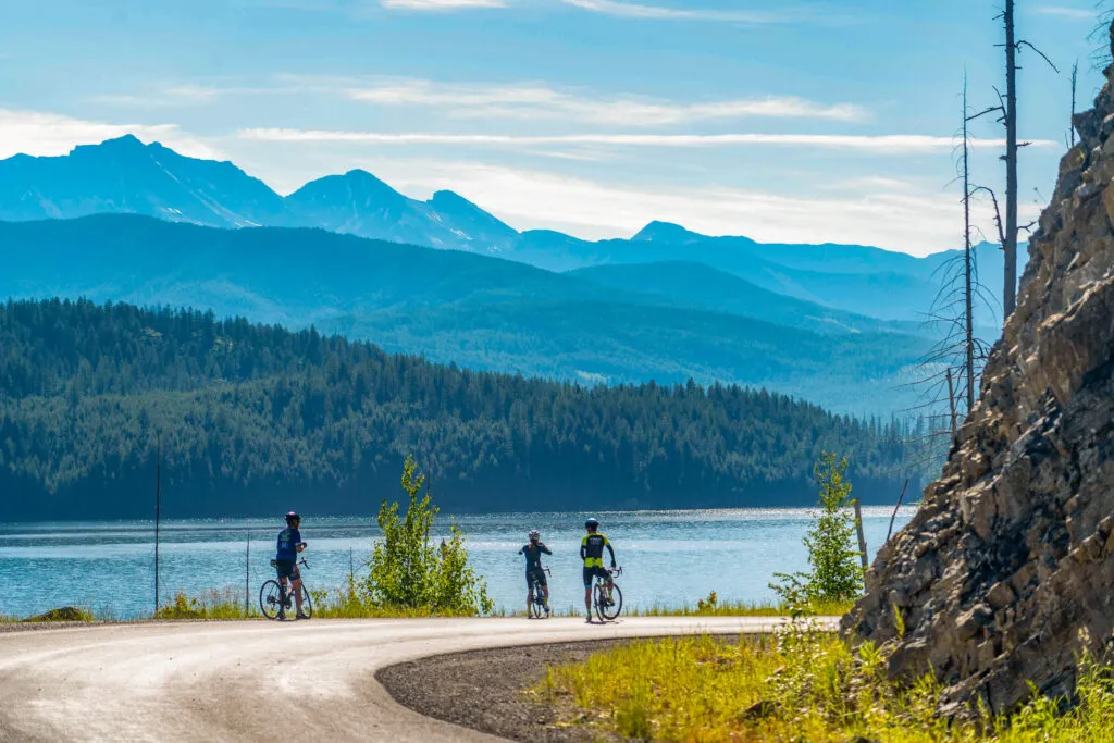 Three cyclists looking out at a glacial lake in Glacier National Park