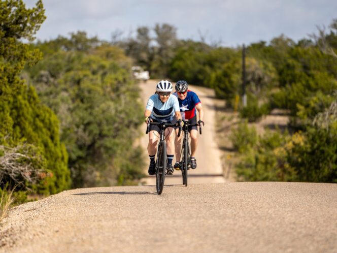 two people riding their bikes up a hill in Texas Hill Country