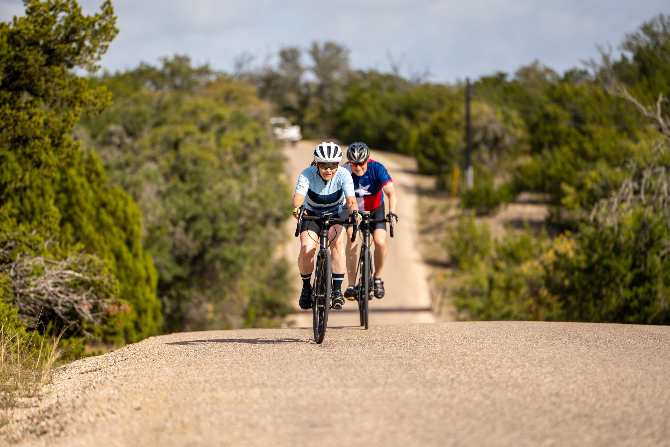 two people riding their bikes up a hill in Texas Hill Country