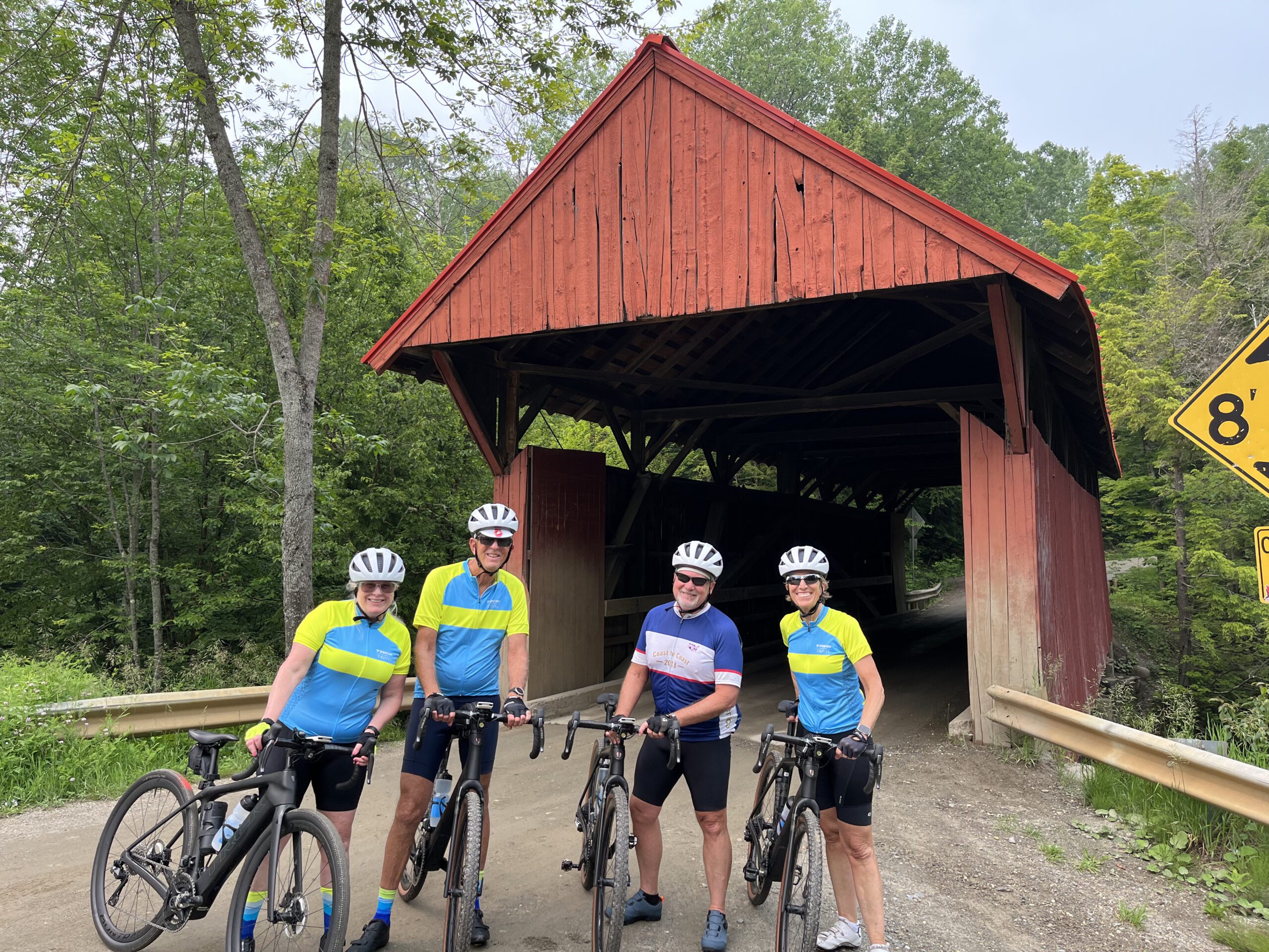 A group of cyclists in front of a covered bridge