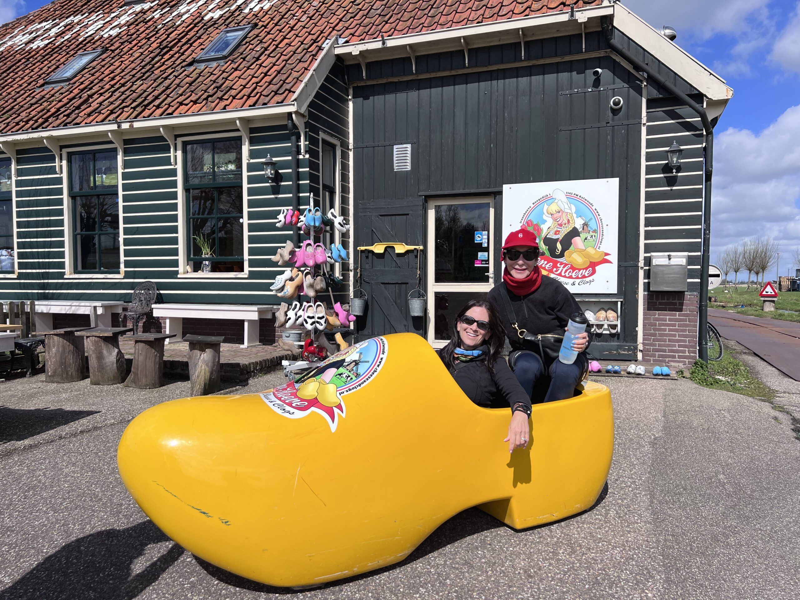 Two women sitting in an oversized wooden Dutch clog.