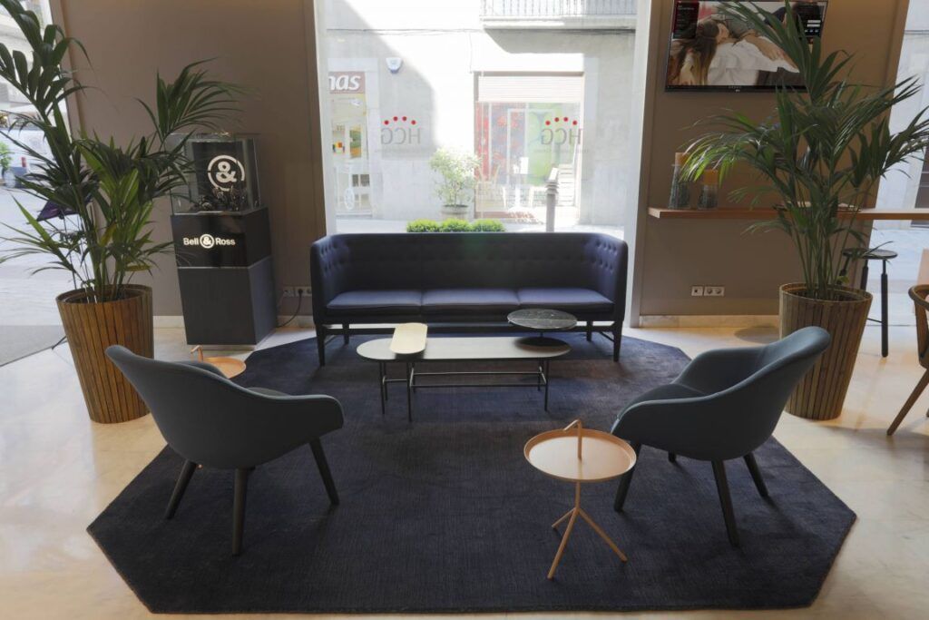 Front lounge of Hotel Ciutat with sofa and two chairs on an area rug.