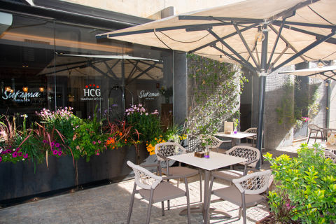 Outdoor patio with flowers, table, and umbrella at Hotel Ciutat