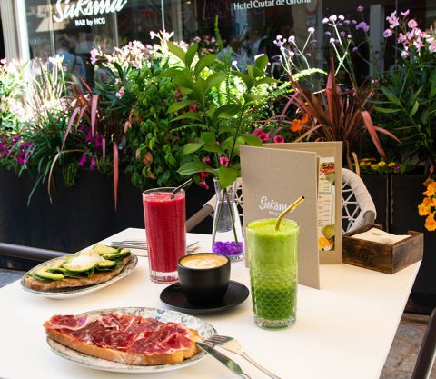 Hotel breakfast smoothies, coffee, and toasts with tropical flowers in the background.