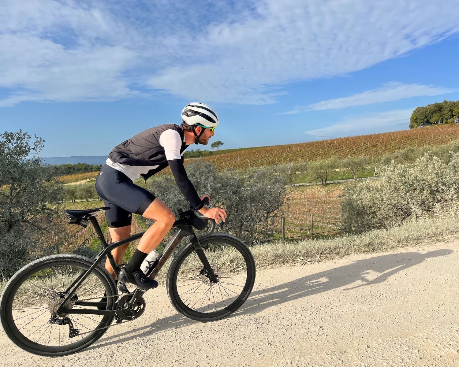 Solo rider on a gravel road with Tuscan landscape in background.