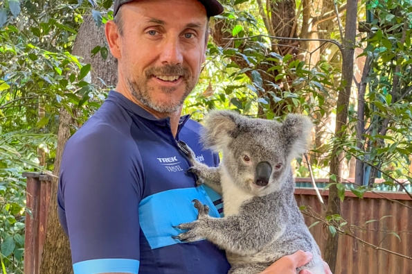 A person in cycling gear holding a koala