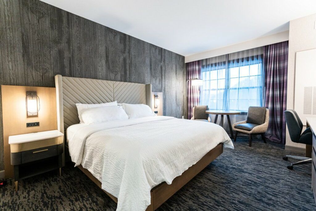 Deadwood Mountain Grand hotel room with double bed, chairs, and wood-panelled feature wall