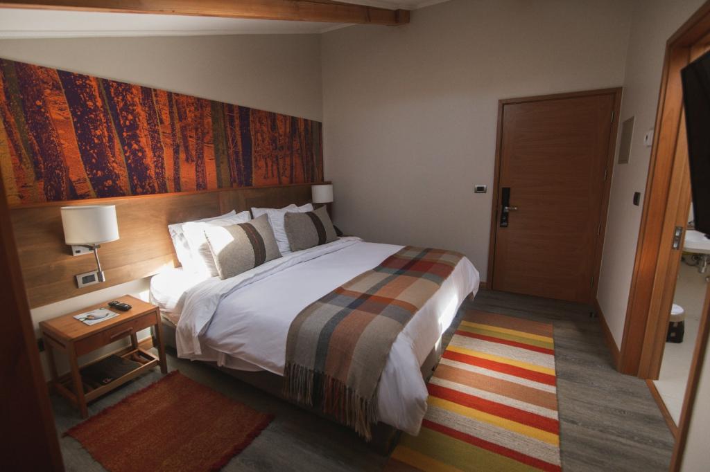 Hotel room with double bed, rug and wood details.
