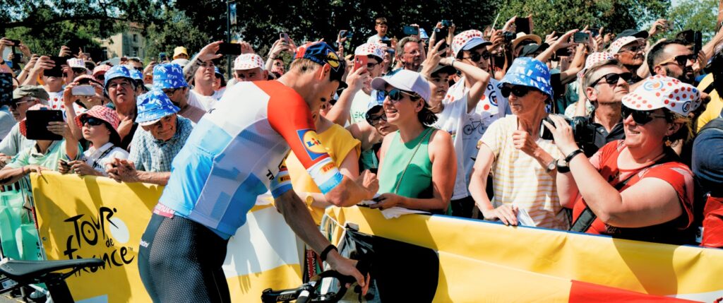 Lidl-Trek rider signing autographs at race barrier