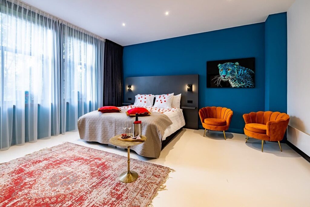 Spacious double bedroom with two stylish chairs and a leopard painting