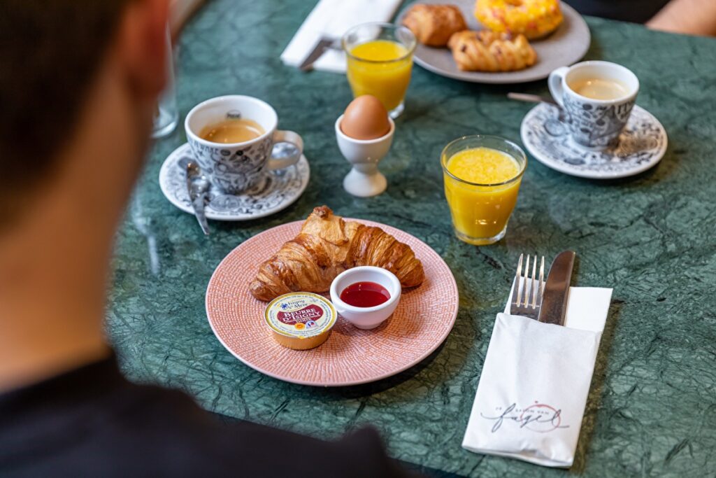 Hotel breakfast table with croissant, boiled egg, juice and coffee