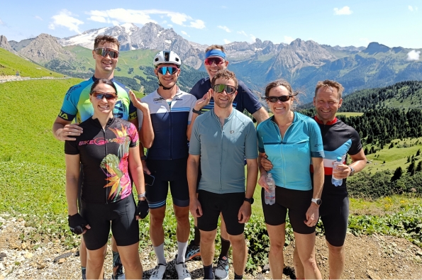 A group of cyclists posing with the Dolomites mountain range in the backgroun