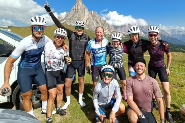 A group of cyclists posing with the Dolomites mountain range in the backgroun