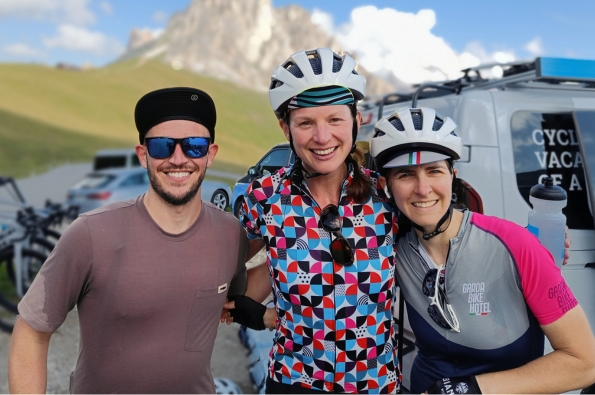 Three cyclists smiling with a mountain in the background