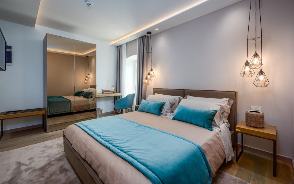 Double bedroom with pendant lighting and large mirror at Hotel San Tommaso