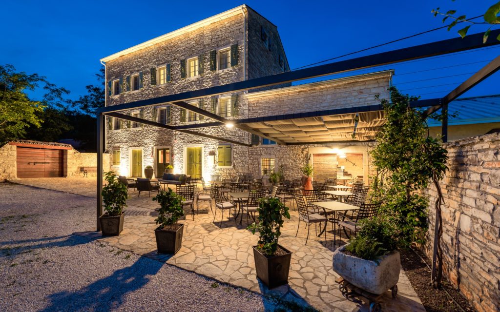 Outdoor dining area and edifice lit at night at Hotel San Tommaso