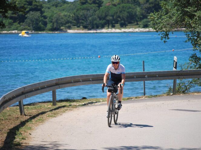 A cyclist riding alongside the sea.