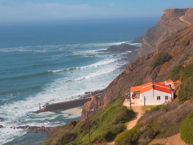 A red-roof house on the side of a cliff by the sea