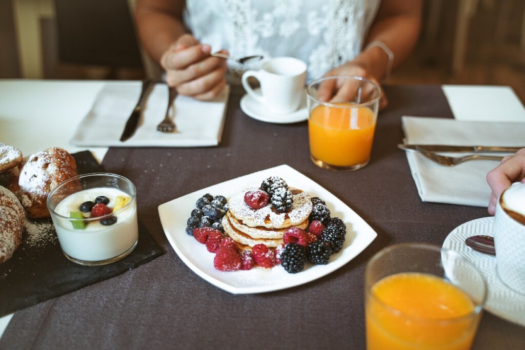 Breakfast table with pancakes, fruit, yoghurt, and juice