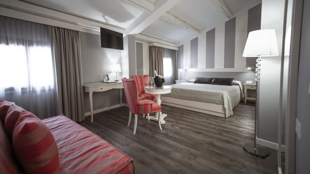 Double bedroom suite with wood flooring and bold striped walls.