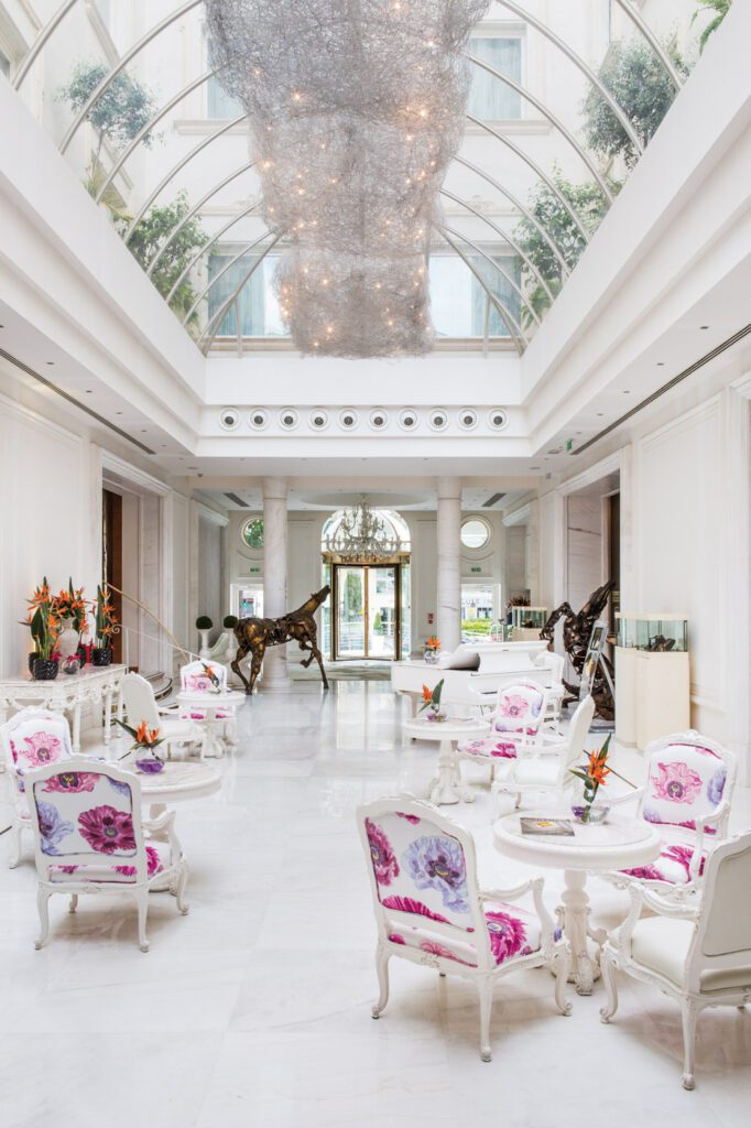 Bright lobby with glass ceiling and floral seating at Hotel Boscolo in Nice