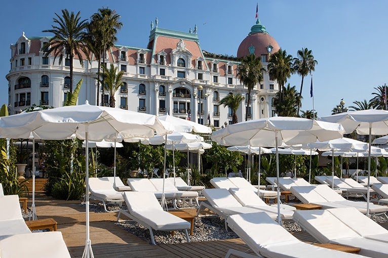 Outdoor view of Le Negresco Hotel with beach lounge chairs and umbrellas