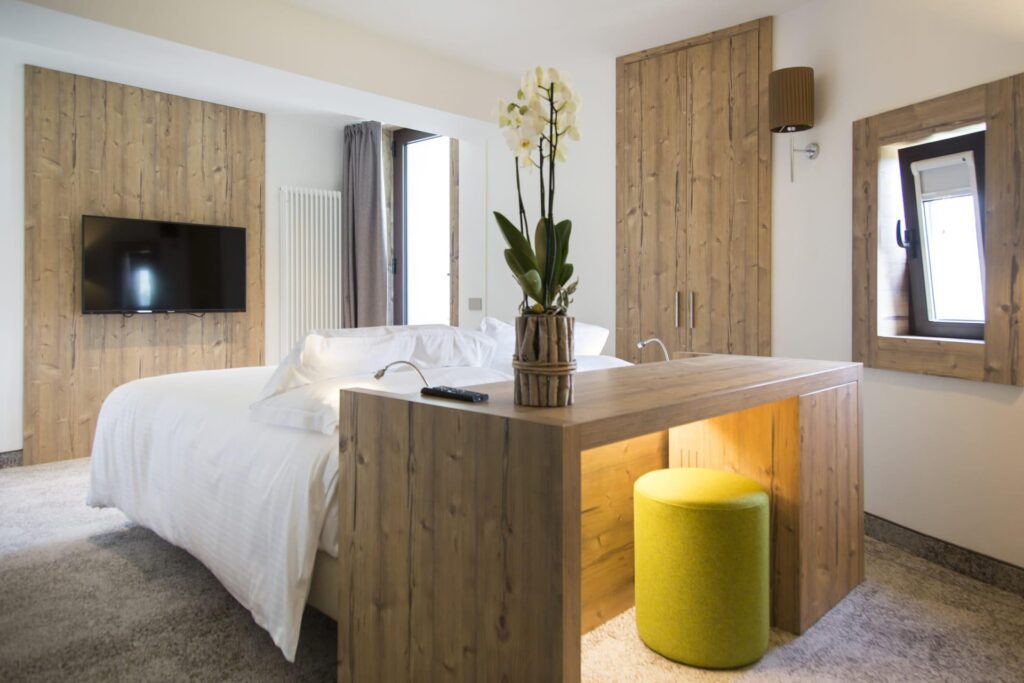 Double bedroom with wood furniture and wall accents at Linta Hotel Wellness & Spa