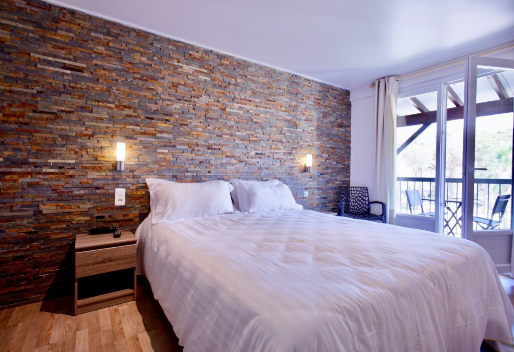 Double bedroom with exposed brick wall and patio at Auberge de Val Mourèze