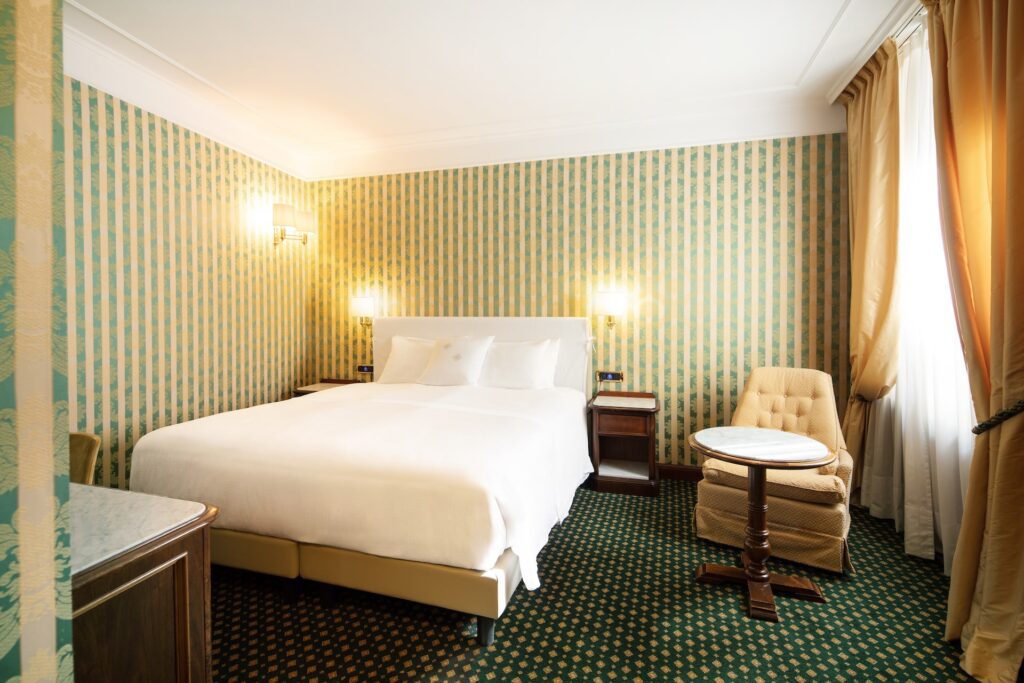 Double hotel room with patterned wallpaper and carpeting