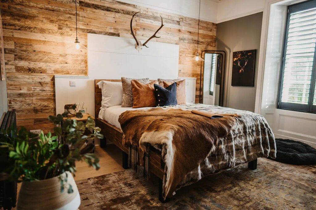 A double bedroom with wood walls, and animal hide on the bed